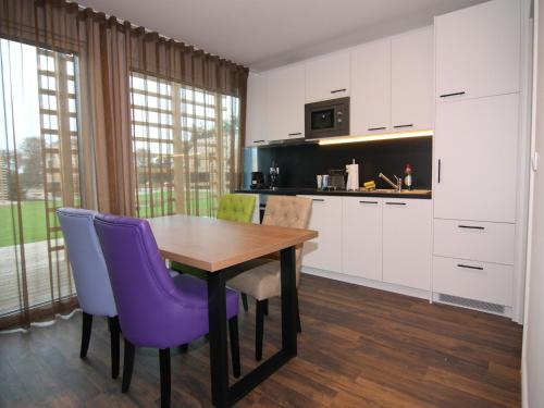 eine Küche mit einem Holztisch und lila Stühlen in der Unterkunft Chalet in Wendorf in Wendorf