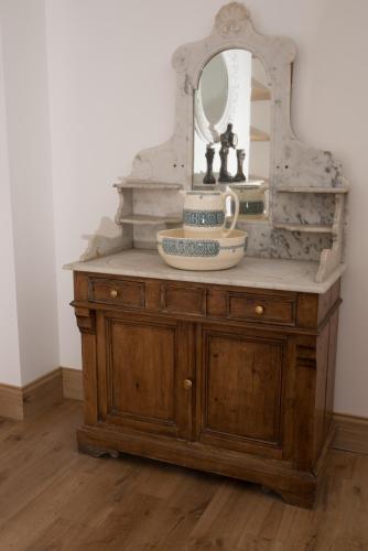 - une commode en bois avec un miroir et un lavabo dans l'établissement Lou Castet de Lussolle - Chambres d'hôtes, à Losse
