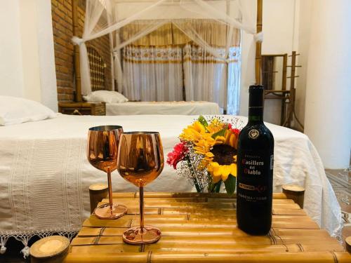 a bottle of wine and two glasses on a wooden table at Hostal Axlan in Puerto Escondido