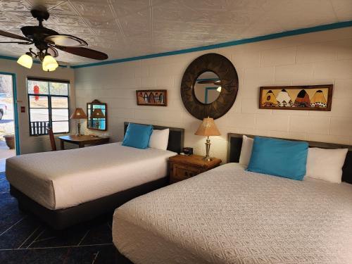a bedroom with two beds and a mirror on the wall at Arrowhead Motel and RV Park in Ruidoso