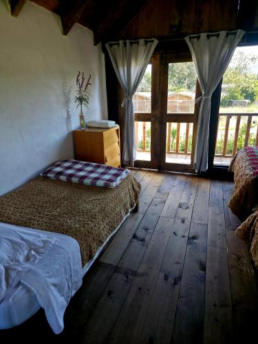 a bedroom with a bed and wooden floors and windows at Cabañas Las orquídeas in Huasca de Ocampo