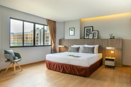 a hotel room with a bed and a chair at Jazzotel Bangkok in Bangkok