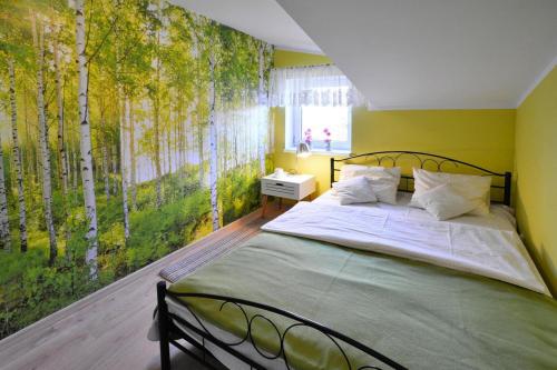 a bedroom with a bed with a mural of trees at Holiday Home near Ko obrzeg with Private Pond in Nieżyn
