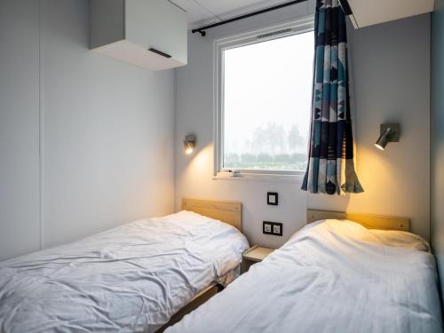 Dos camas en una habitación pequeña con ventana. en Chalet in Nature, Friesland, en De Veenhoop