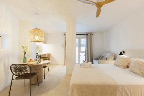 a white bedroom with a bed and a table at Vacança beach in Denia
