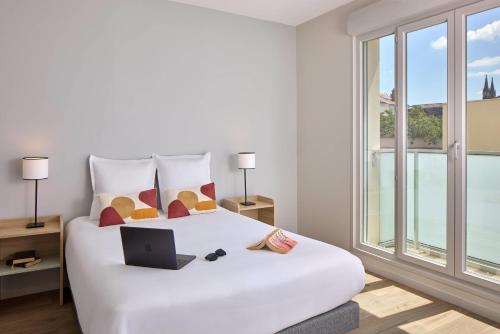 Un dormitorio con una cama blanca y una computadora portátil encima. en Quality Suites Reims - Saint-Thomas, en Reims
