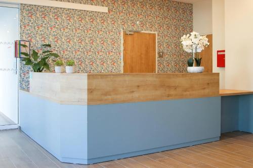 Un mostrador de recepción en una oficina con flores en la pared. en Quality Suites Reims - Saint-Thomas, en Reims