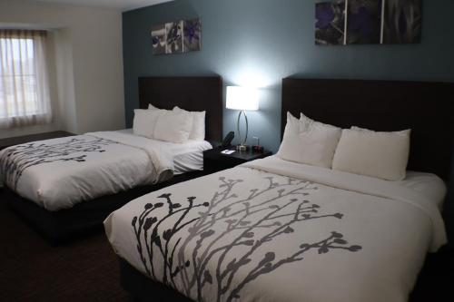 ein Hotelzimmer mit zwei Betten mit weißen Laken in der Unterkunft Sleep Inn Marion - Cedar Rapids in Cedar Rapids