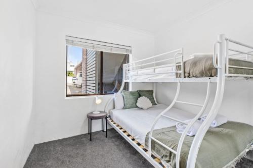 Surf's Up Sawtell في ساوتيل: غرفة نوم بها سريرين بطابقين ونافذة