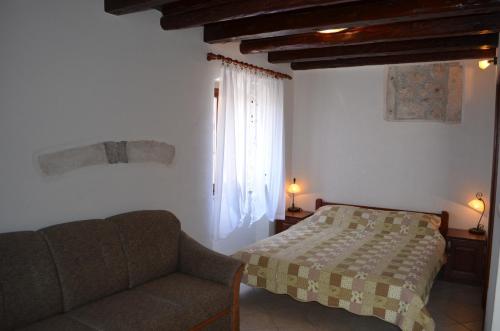 a bedroom with a bed and a couch and a window at Apartments Hedviga in Krk