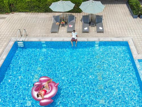 a person standing in a swimming pool with a pink toy in a swimming pool at Jazzotel Bangkok in Bangkok