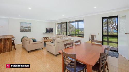 a living room with a wooden table and a dining room at Cuttagee Beach Cottage 1 - Tathra Bermagui Rd 3521 in Barragga Bay