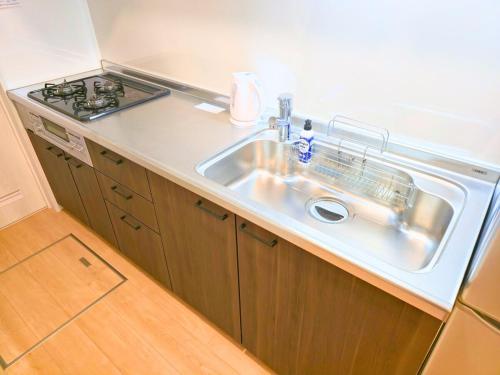 a kitchen with a sink and a stove at 新大阪ゲストハウス 新大阪駅徒歩5分のリノベーション貸切宿 in Osaka