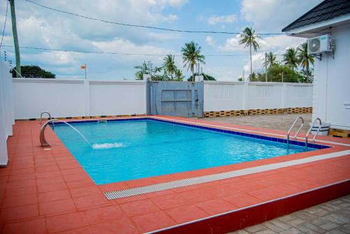 una piscina con acqua blu su un pavimento di piastrelle rosse di BNJ Royal Palace a Dar es Salaam