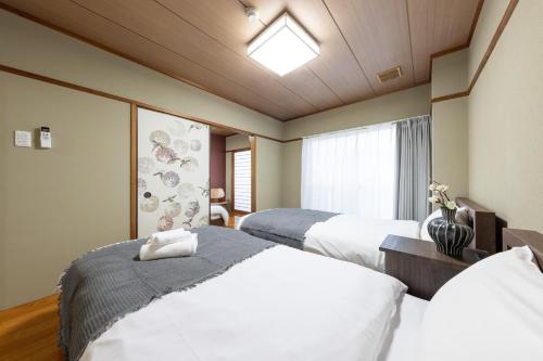 a hotel room with two beds and a window at HITOYADO kanazawa in Kanazawa