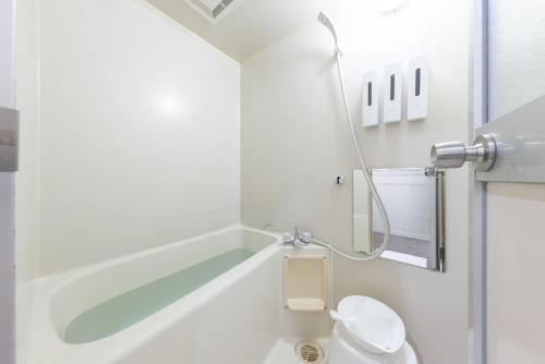 a white bathroom with a toilet and a sink at HITOYADO kanazawa in Kanazawa