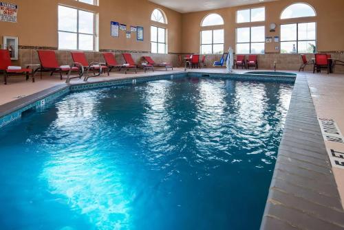 a large swimming pool with red chairs in a building at Baymont by Wyndham Lubbock in Lubbock
