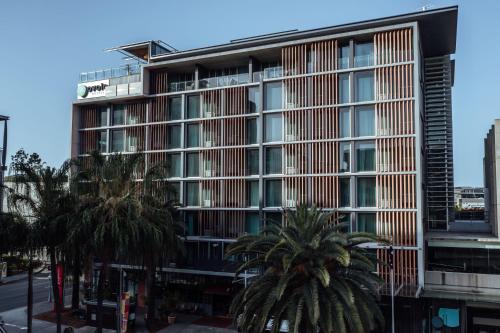 a tall building with palm trees in front of it at Ovolo Brisbane Fortitude Valley, a Wyndham Hotel in Brisbane