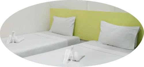 Duas camas com almofadas brancas num quarto em Sulit Budget Hotel near Dgte Airport Citimall em Dumaguete