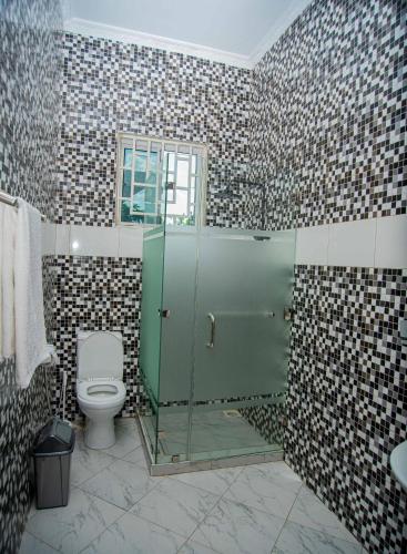 a bathroom with a shower with a toilet and a sink at BNJ Royal Palace in Bagamoyo