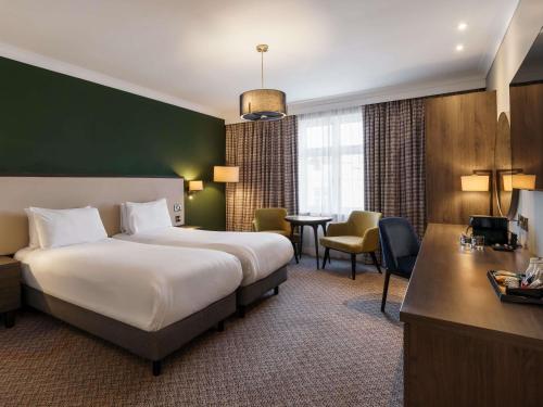 a hotel room with a large bed and a desk at Mercure Blackburn Dunkenhalgh Hotel & Spa in Blackburn