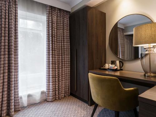 a room with a desk and a chair and a window at Mercure Blackburn Dunkenhalgh Hotel & Spa in Blackburn