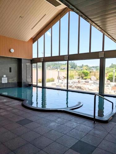 a large swimming pool in a large building with windows at glampark Verga in Hokuto