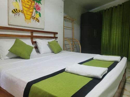 Un dormitorio con una cama con almohadas verdes y blancas. en Beehive mountain resident, en Kandy