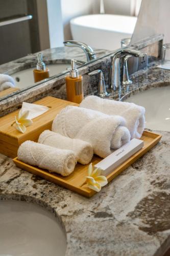 a wooden cutting board with towels and flowers on a sink at Villa Alinea in Tanah Lot