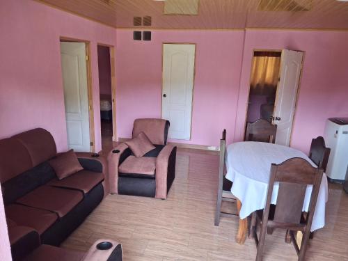 ein Wohnzimmer mit rosa Wänden, einer Couch und einem Bett in der Unterkunft Casa non in Guatemala