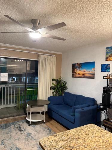 a living room with a blue couch and a ceiling fan at Seawall Breeze One bedroom Condo in Galveston in Galveston