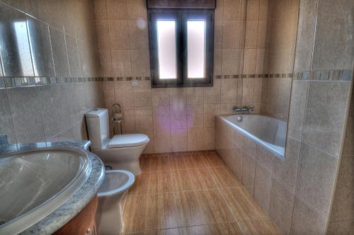 a bathroom with a tub and a toilet and a sink at Casa das Gêmeas in Sabuzedo