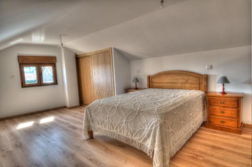 ein Schlafzimmer mit einem Bett, einer Kommode und einem Fenster in der Unterkunft Casa das Gêmeas in Sabuzedo