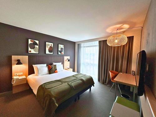 a hotel room with a bed and a desk at Mercure Valenciennes Centre in Valenciennes