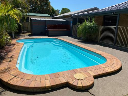 a swimming pool in a yard with a brick patio at Coastal Palms in Yamba