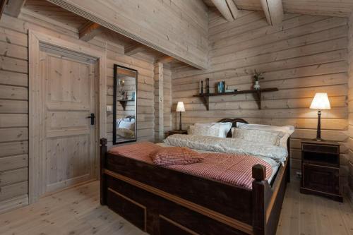 een slaapkamer met een bed en een houten wand bij Timber Cabin With Panoramic Views At Spåtind in Etnedal