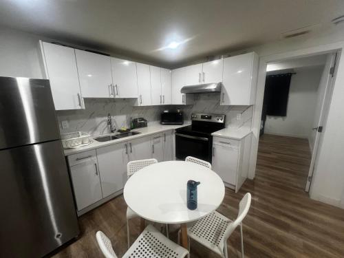 Una cocina con gabinetes blancos y una mesa y sillas blancas. en Private room in Basement suite, en Edmonton