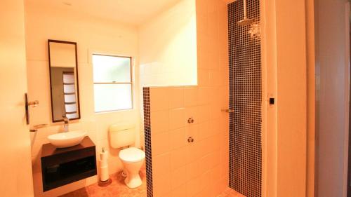 un bagno con lavandino, WC e specchio di Lakehouse Akolele 19 Flower Circuit- Wallaga Lake Bermagui a Central Tilba