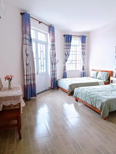 a bedroom with two beds and two windows at Thuy's homestay in Vung Tau