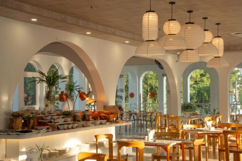 a restaurant with tables and chairs and windows at The Up Hotel Phu Quoc Island - The Poolside Escape in Phu Quoc