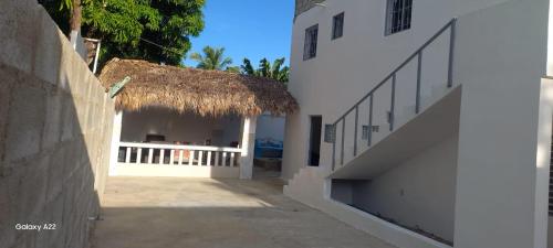 a white building with a straw roof and stairs at Jeremi Apartamentos in Colorado