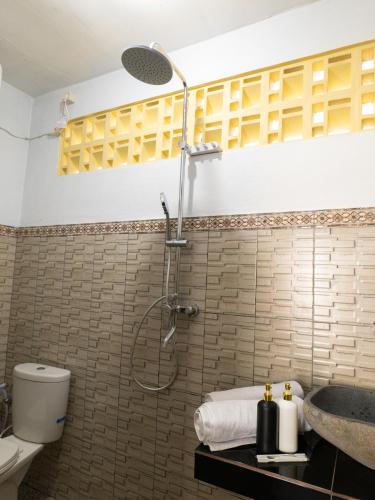 a bathroom with a shower and a toilet and a sink at Lumbung Lodge Lovina in Balian