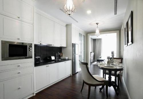 a kitchen with white cabinets and a table and a dining room at Rongratana Executive Residence Bangkok in Bangkok