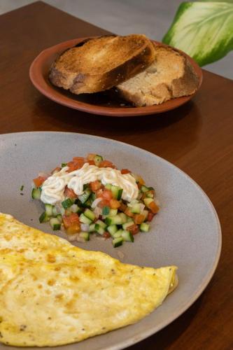 a plate of food with a omelet and a piece of bread at Mellow Hostel Sri Lanka in Ahangama