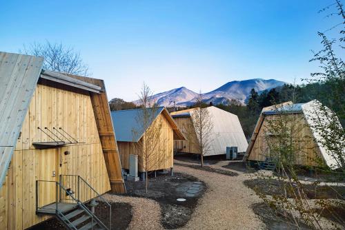 a row of wooden buildings with mountains in the background at SANU 2nd Home 軽井沢1st in Oiwake