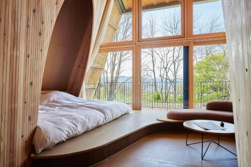 a bed in a room with a large window at SANU 2nd Home 軽井沢1st in Oiwake