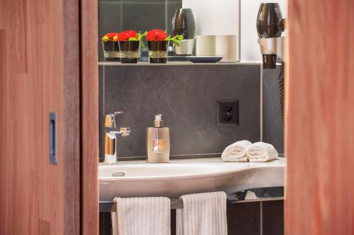 ein Bad mit einem Waschbecken, Handtüchern und Blumen in der Unterkunft Hotel Restaurant Rhy in Oberriet
