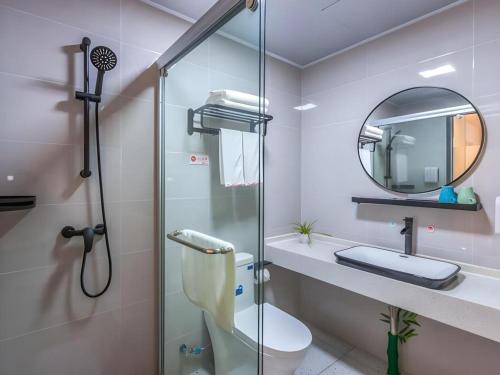 a bathroom with a shower and a toilet and a mirror at Shell Hotel Wuxi Gonghu Avenue Vientiane City in Zhongqiao
