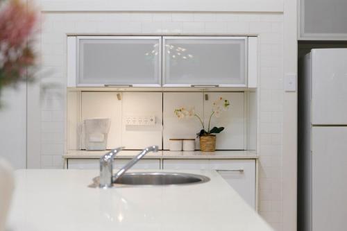 a kitchen with a sink and white cabinets at Spacious 3BR Family Home at Central Chatswood in Sydney