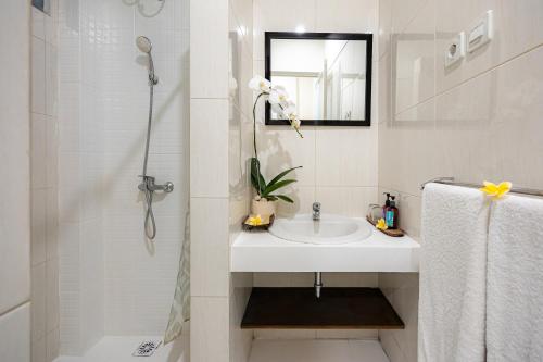 a white bathroom with a sink and a shower at Bali True Living in Denpasar